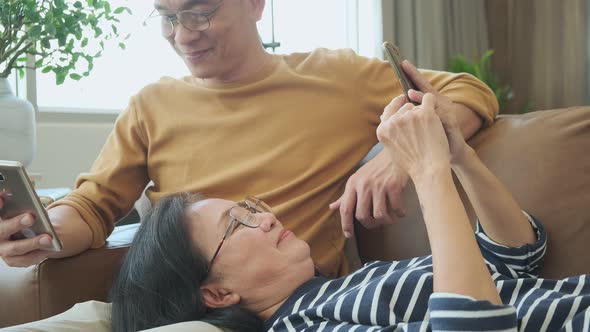 Happy elderly grandfather and grand mother relax casual use smartphone alt
