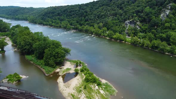 The Potomac River near Harper's Ferry, West Virginia as a train crosses the river on a bridge. alt