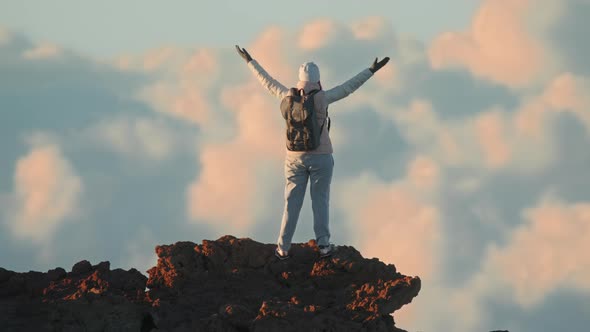Woman with Backpack on Top of Cinematic Mountain Summit Above Clouds Sunset alt
