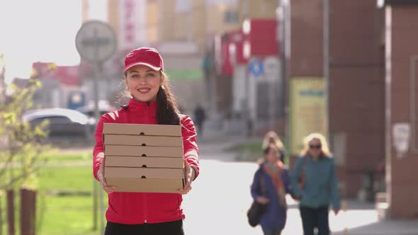 Courier girl with pizza on crowded street