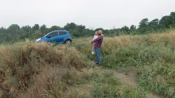 Wide Shot of Smiling Happy Young Bearded Father Holding Cute Little Daughter on Hands Talking alt