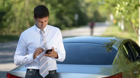 Young Businessman Browsing Net with Phone Outdoors alt
