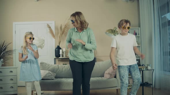 Grandmother is Dancing with Her Grandkids at Home alt