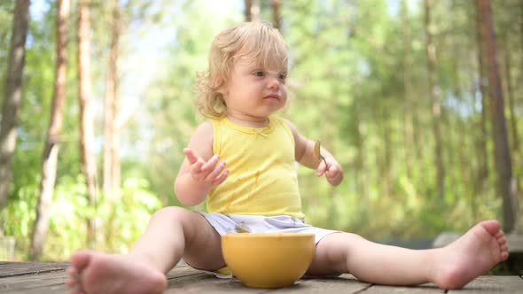 Little Funny Cute Blonde Girl Child Toddler with Dirty Clothes and Face Eating Baby Food Fruit or