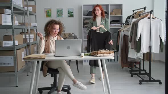 Sale of Goods Via Internet Young Salesperson Together with Female Colleague Show Clothes to Client alt