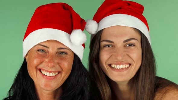 Happy Women in Santa Claus Hats Laughing Joyfully To the Camera alt
