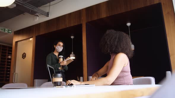 Two Businesswomen In Masks Greet By Touching Elbows In Office During Health Pandemic