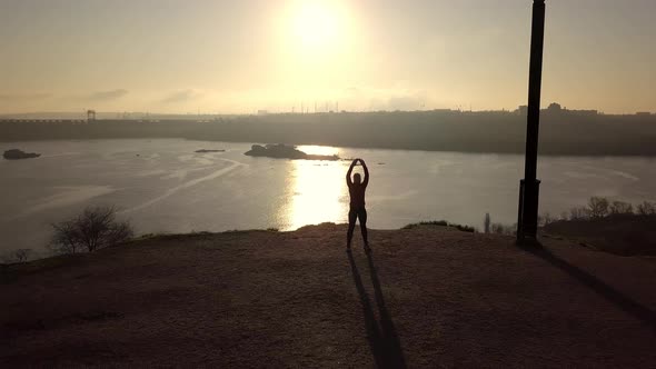 Woman Practicing Martial Arts at Riverside at Sunset