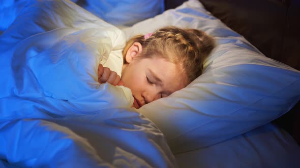 The Pretty Little Girl Naps in Bed Sees a Pleasant Sleep and Smiles alt