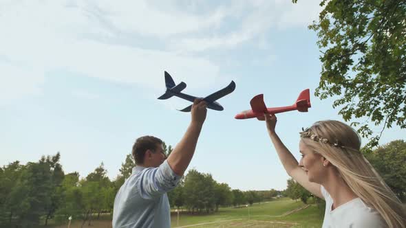A Guy and a Girl Launch Toy Airplanes in the Sky alt