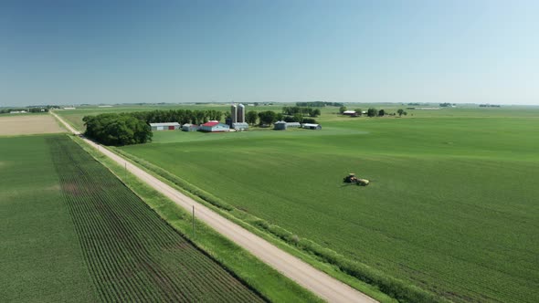Aerial panorama, tractor spraying pesticide onto fresh crops in farmland countryside. Series alt