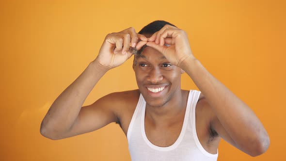 Young Man with Dark Skin Poses for the Camera Removing a Cosmetic Mask From the T-zone of the Face alt