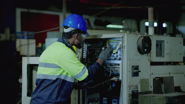 Caucasian maintenance engineer is using a torch to light a control cabinet to maintain