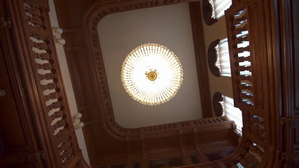a Large Beautiful Chandelier in the Center of a Wooden Spiral Staircase