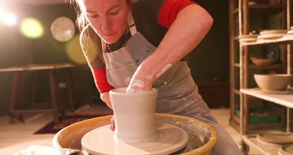 Female potter forming a bowl on pottery wheel