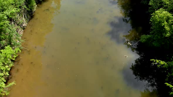 aerial footage of drone flying over the Illinois and Michigan canal with murky brown water and brigh alt