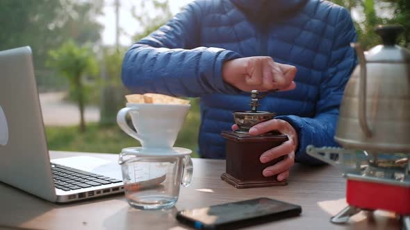 Slow motion Man hand grinding coffee beans with manual stainless steel grinder alt