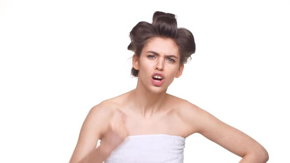 Topless Upset Caucasian Girl with Hair Curlers Standing Over White Background in Slowmotion alt