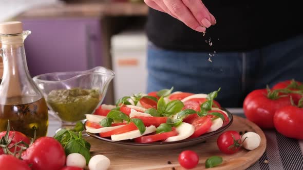 Salting Caprese Salad  Mozzarella Cheese Balls Sliced Cherry Tomatoes and Basil alt