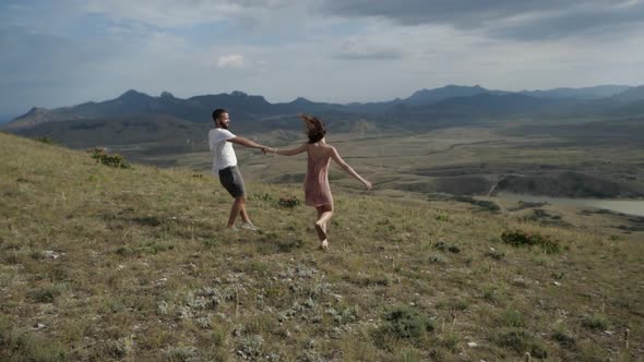 The Happy Couple Holding Hands, Running Along a Plain Under the Overcast Sky