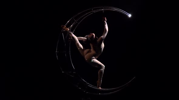 Acrobat Rotates on a Metal Structure in a Vertical String. Black Background alt