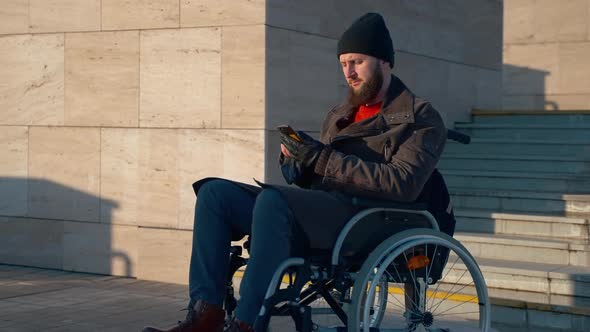 Disabled Man Spending Morning Outdoor in the City and Using Phone alt