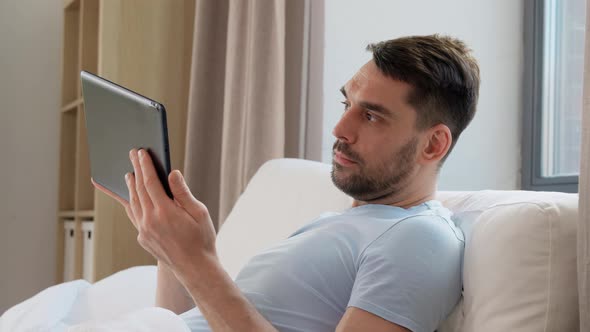 Man with Tablet Computer in Bed at Home Bedroom