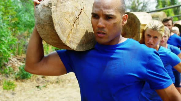 Fit people carrying tree log in boot camp 4k alt