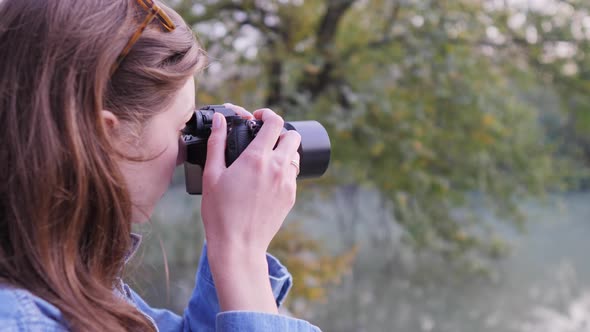 A Young Female Photographer in Nature Shoots Wildlife in the Fall in the Woods