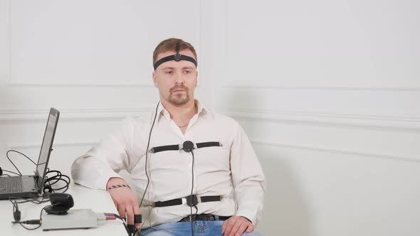 A Man Answers the Questions of the Expert Polygraph Sitting on a Chair in an Office alt