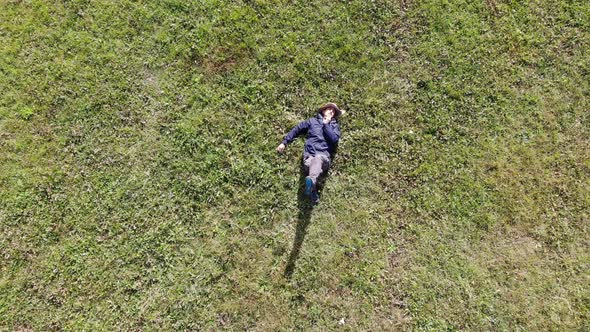 Bird Eye View Shot of a Caucasian or Hispanic Man Laying Down on Green Grass on a Sunny Day