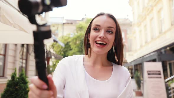 Vlogging. Woman filming video on camera at city street alt