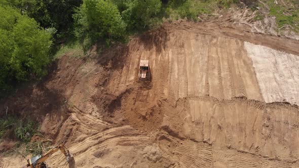 Aerial view of bulldozer flattening surface on further construction site