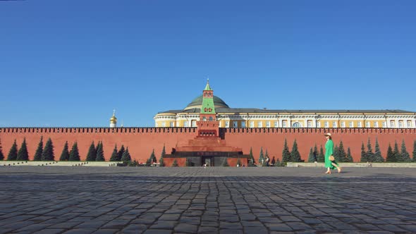 Beautiful girl in a green dress on an empty Red square in summer alt