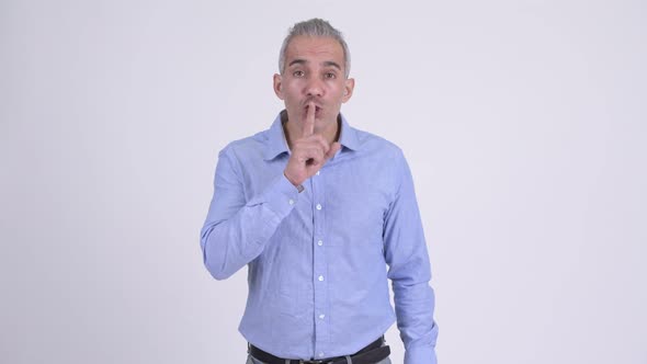 Handsome Persian Businessman with Finger on Lips Against White Background alt
