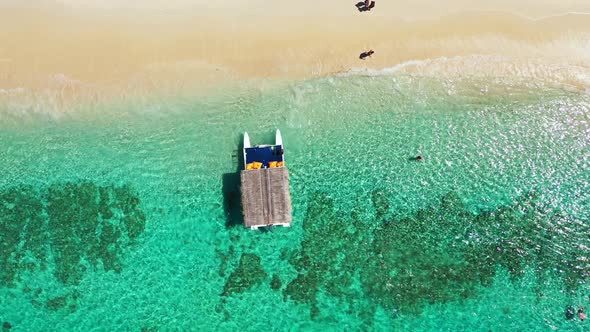 Touring boat with straw roof floating over calm clear water of turquoise sea over beautiful pattern alt