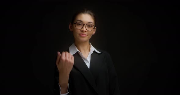 Businesswoman in Glasses and a Black Jacket Shows a Come Here Hand Gesture
