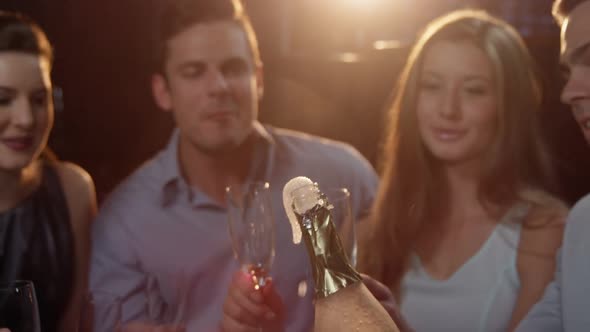 Group of smiling friends interacting while having a glass of champagne at bar alt
