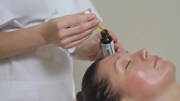 Applying Massage Oil on the Forehead of a Beautiful Brunette Woman in Spa Salon alt