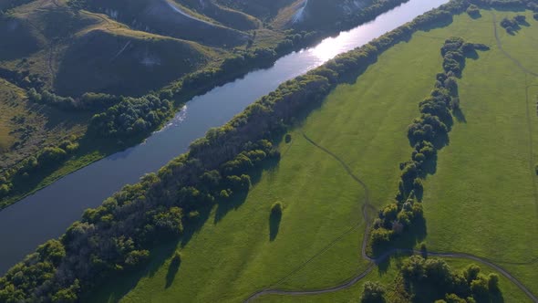 Aerial Footage of a Large River Surrounded By Green Fields and Hills alt