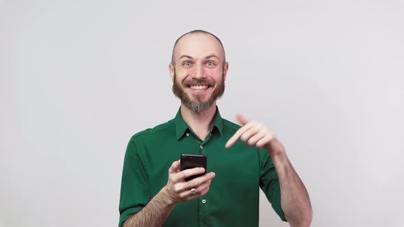 Handsome happy bearded man using mobile phone over white background.