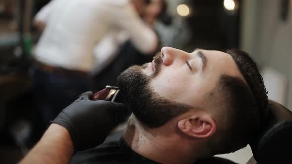 Barber Shaves the Beard of the Client with Trimmer alt