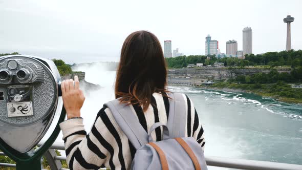 Camera Slides Behind Happy Tourist Woman with One Hand on Coin Operated Binoculars at Epic Niagara alt