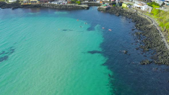 Tourists kayaking in the clear blue sea of Jeju Island. alt