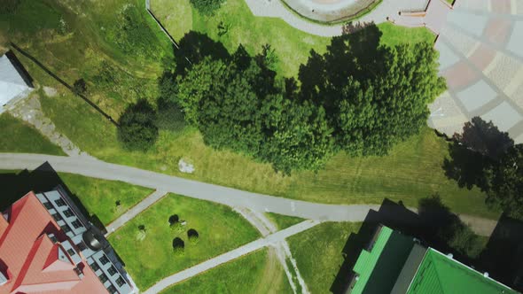 Flight over a provincial town. An ancient tower among the multi-colored roofs of houses. Aerial phot alt