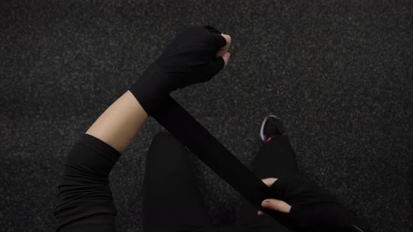 Closeup of a Young Woman Bandaging Her Fists with a Black Bandage in the Gym alt