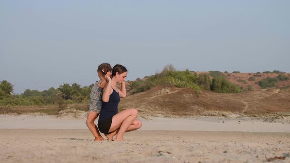 Young Sporty Mother with Little Daughter Doing Gymnastic on the Beach