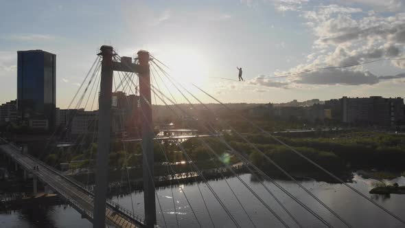 A Man Walks on a Rope Stretched Between the Supports of the Bridge at High Altitude