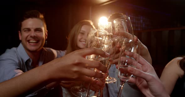 Group of smiling friends sitting on sofa and toasting a glasses of champagne alt