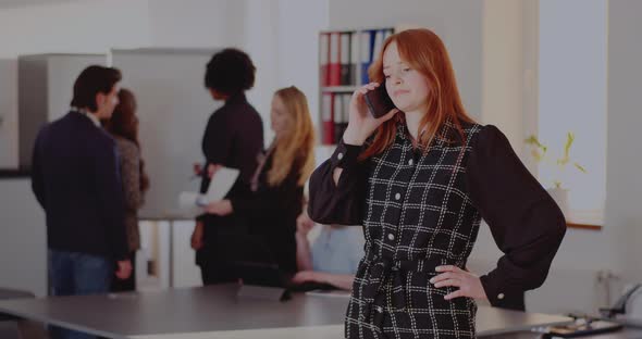 Businesswoman Talking on Smart Phone in Office alt